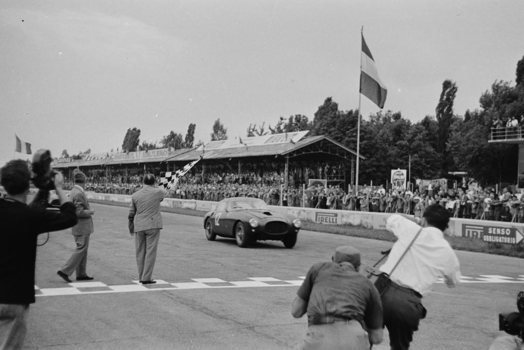 Crossing the finish line at the 1953 Monza Grand Prix, the winning Ferrari 250 MM Pininfarina Berlinetta driven by Luigi Villoresi, is portrayed perfectly by Mailander with the checkered flag waving victoriously off to the side. 